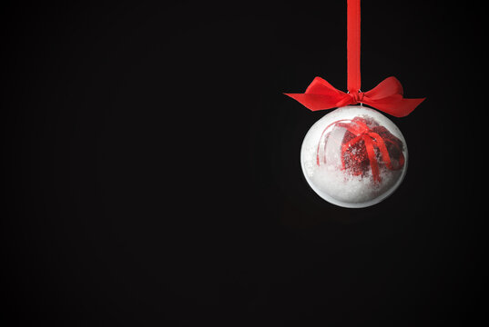 Glass Christmas ball with red bow on black background. Festive ornament - Powered by Adobe