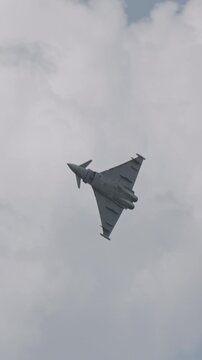 Fast fighter jet during high speed combat maneuvers with clouds