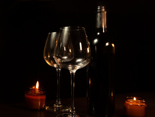 Still life of two empty clear wine glasses near romantic burning flame fire candles on a table on dark backround. Closeup decor concept of Christmas holiday celebration