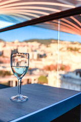 Glass of white wine on table in sunlight. Atmosphere of delightful event. Vertical photo