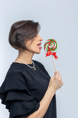 Portrait of beautiful woman with sweets round lollipop in her hand. Vertical photo.