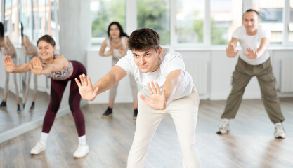 Group of young women and men enjoying active dance movement in modern studio