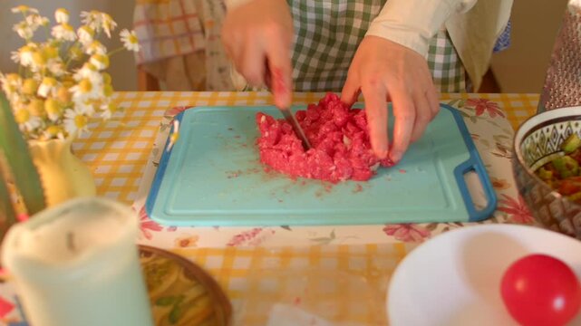 meat prep visualization, precise hand chopping raw meat on colorful kitchen board with ingredients nearby, methodically slicing raw meat into uniform pieces on bright cutting board with ingredients