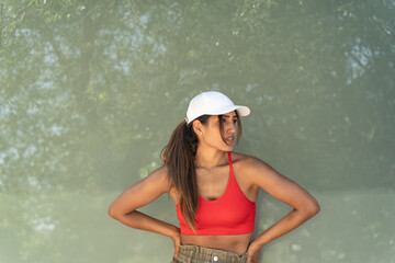 Young woman posing with hands on hips, looking away against a soft green background