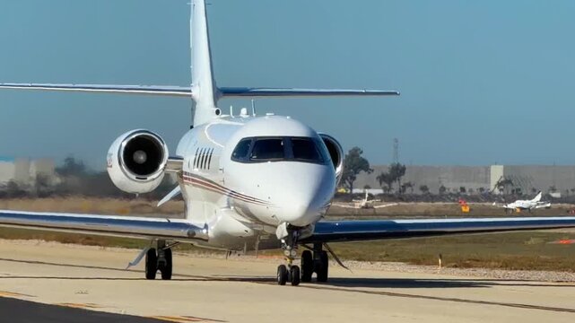 A medium private jet taxis on a sunny day with the sun reflecting off of its polished surfaces.