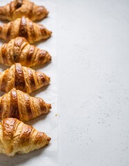 Freshly baked croissants lined up on parchment paper, golden buttery pastries with copy space, minimalist breakfast concept