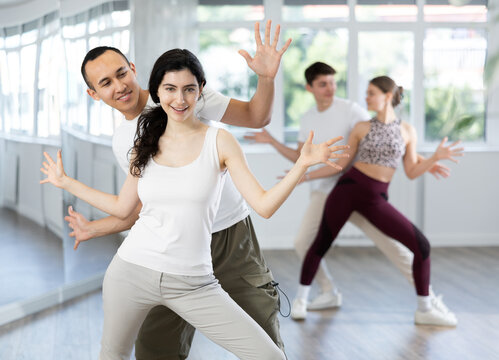 Happy young woman and man enjoying active boogie-woogie dance in modern studio. Social dancing concept