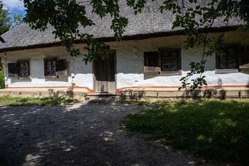 Fototapeta premium Traditional rural house with white walls and thatched roof in summer