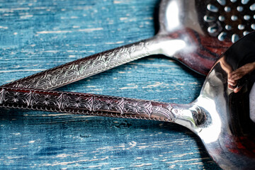 close-up of a traditional ladle and slotted spoon with a pattern.