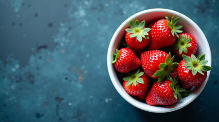 Fresh strawberries in white bowl on dark blue surface, vibrant fruit visual for healthy eating, nutrition, food styling, organic produce and culinary freshness