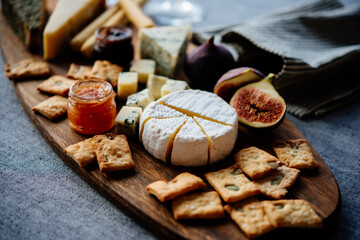 Wooden board with different kinds of cheese and appetizers served for dinner or party.