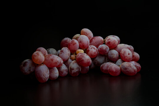 Stylish shot of fresh red grapes on a black background. Perfect for winemaking or gourmet food concepts, with ample copy space for text. Photo