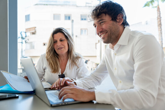 Financial advisor explaining investment options to a woman, using a laptop and documents to plan personalized financial strategies