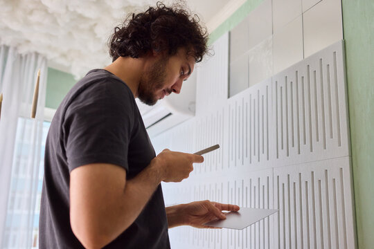 Joyful homeowner redesigns textured wall effortlessly, Homeowner happily personalizes textured wall with self installed decorative mirror tiles for stylish appeal