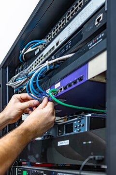 Technician connecting ethernet cables in network server rack, Florida, USA