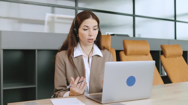 Angry Consultant assisting clients through online calls in a modern office environment using a laptop and headphones