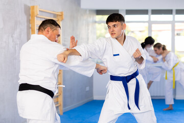 Fototapeta premium Active young male attendee of karate classes fighting with middle-aged man during workout session