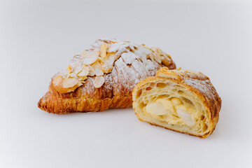 Almond croissant cut in half with creamy filling and powdered sugar on white background