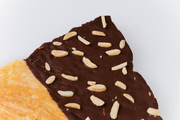 Close-up of chocolate glazed croissant with almond slices on white background