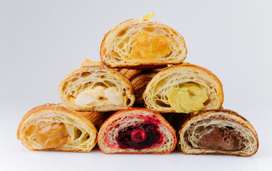 Assorted filled croissant halves with colorful cream and jam layers stacked pyramid style