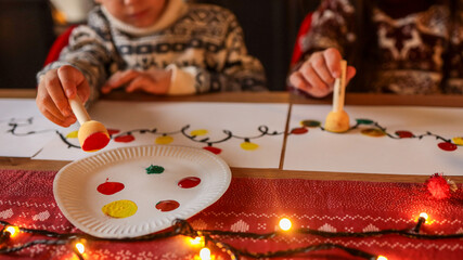 Children painting Christmas lights on paper at a festive holiday table
