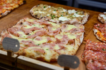 Authentic Italian pizza in a restaurant display window in Rome, Italy.  Different type of traditional Roman styple pizza . 