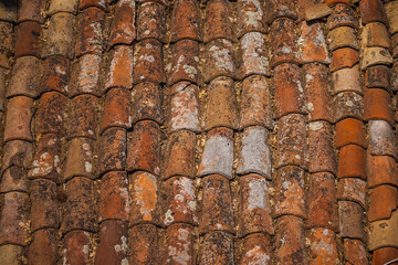 Close-up view of old clay roof tiles with natural weathering and lichen texture on a traditional building in Bulgaria.