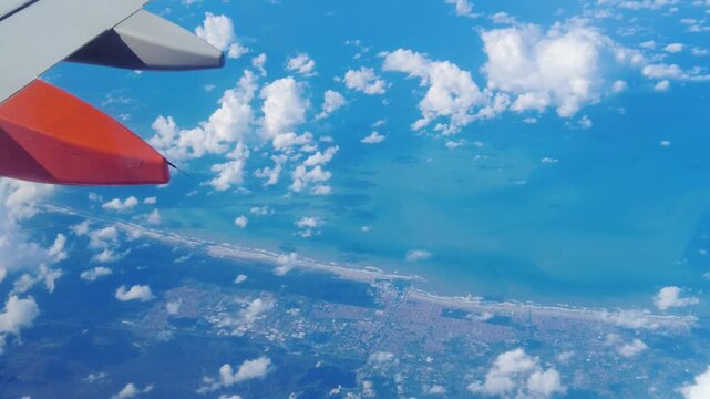 sweep wing plane air thick clouds below land towns sides ocean meeting horizon under blue light to left right closeup airplane perspective civilization structure atmosphere observation 