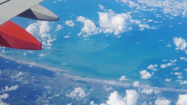 perspective wing plane air thick clouds below coastal land towns meeting horizon blue light to left right closeup airplane civilization structure composition reflection 