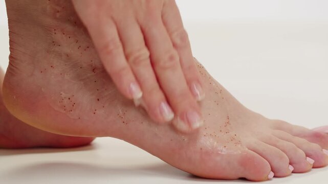 Woman using cream cosmetics in bathroom, applying moisturizing cream to her leg while sitting in a bathtub. Skincare and body care routine, middle aged woman use scrub macro close up. 