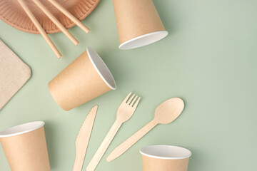 Eco - Friendly Tableware on Green Background. Top View. Plastic free Set of Brown Paper Utensil. Street Food Recyclable Packaging. Zero waste Paperware. Mockup. Disposable Take out Cup, wooden cutlery