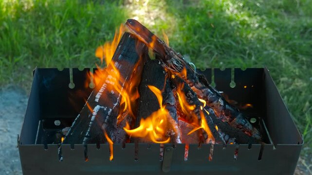 Fire flames in box for homemade barbecue outdoor. A view of handmade fire on logs in the metal box during bbq time