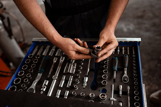 Skilled hands organizing a toolbox filled with various hand tools in a workshop setting - Powered by Adobe