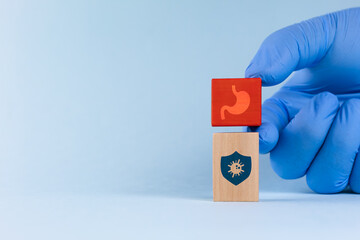 A doctor's hand holds a wooden cube with a stomach icon. Concept of digestive health, prevention, and awareness of stomach infections.