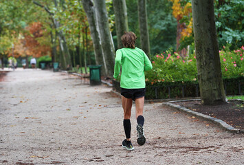 Corredor runner de maratón entrenando footing en pantalón corto por el parque por camino de...