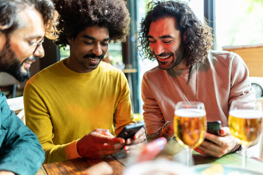 Group of friends enjoying drinks and looking at smartphone at a bar, sharing a moment of leisure and connection