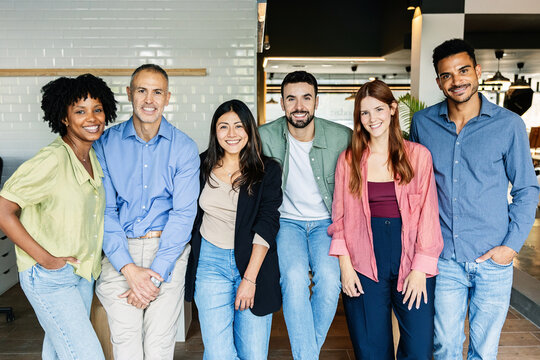 Group of diverse coworkers smiling together at the office. Multiracial team of professionals collaborating and enjoying teamwork. Business and corporate lifestyle concept.