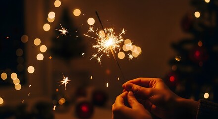 Close-up of hands holding a bright, glittering sparkler amidst blurred warm festive lights, symbolizing joy and celebration during holiday season