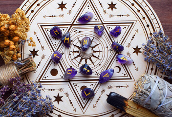 Rose quartz crystals and Scandinavian runes made from natural amethyst, along with dried lavender herbs, on a wooden altar for divination. Divination, witchcraft, and spiritual esoteric practice.
