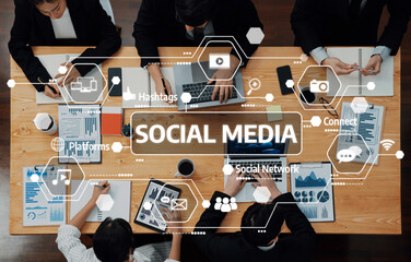 A dynamic business meeting centered on social media strategies, showcasing digital tools and collaborative efforts by a team of professionals around a wooden table. Amity
