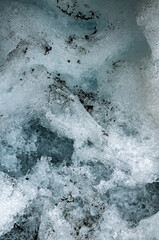 Turquoise glacial ice forming intricate abstract shapes revealing layered blue and white textures within frozen winter wilderness landscape
