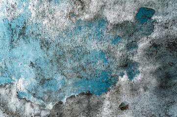 Turquoise glacial ice forming intricate abstract shapes revealing layered blue and white textures within frozen winter wilderness landscape