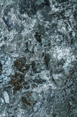 Turquoise glacial ice forming intricate abstract shapes revealing layered blue and white textures within frozen winter wilderness landscape