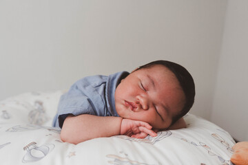 Cute newborn baby boy sleeping peacefully in white crib and soft nest. Close-up of infant resting on bed, symbolizing childhood innocence, comfort, and family love. Perfect for baby care themes.