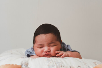 Cute newborn baby boy sleeping peacefully in white crib and soft nest. Close-up of infant resting on bed, symbolizing childhood innocence, comfort, and family love. Perfect for baby care themes.
