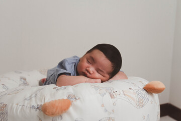Cute newborn baby boy sleeping peacefully in white crib and soft nest. Close-up of infant resting on bed, symbolizing childhood innocence, comfort, and family love. Perfect for baby care themes.