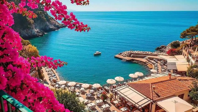 High-angle view of a picturesque cove on the Amalfi Coast, Italy, with vibrant pink bougainvillea, a seaside restaurant, and turquoise water.