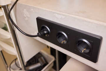Fototapeta premium Power hub setup, Closeup of mounted power strip with multiple connections and cables, IT technician arranging cords and connecting devices on cluttered tech workstation