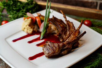 Savory lamb chops are beautifully plated with fresh vegetables and a rich sauce, showcasing the vibrant flavors of Georgian cuisine in a charming restaurant setting