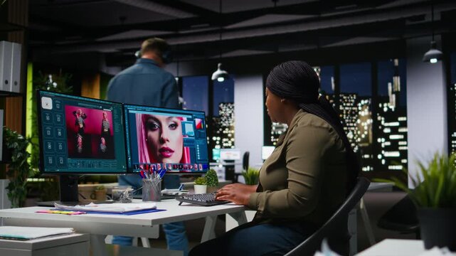 African american photographer using photo editing for digital design, dual monitors show advanced editing software for designer working on image retouching, contrast adjustments. Camera A.